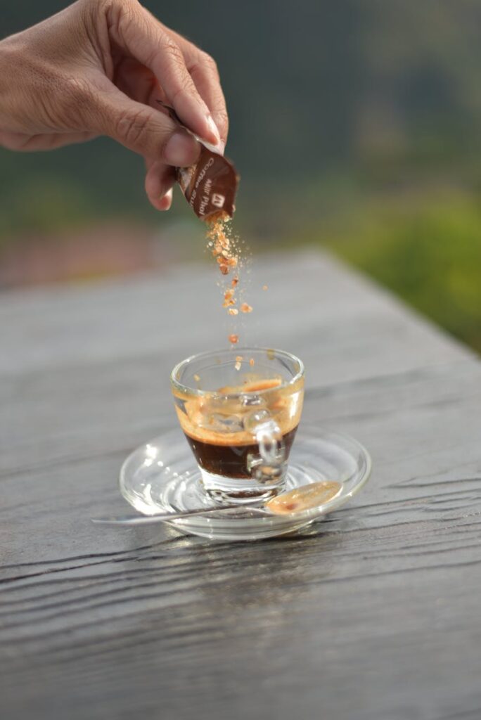 person pouring sugar in coffee